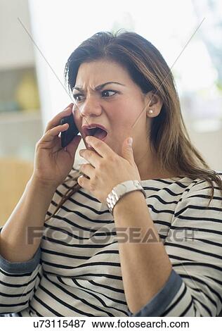 Surprised woman sitting on sofa with mobile phone View Large Photo Image Stock Photo - Surprised woman sitting on sofa with mobile phone. Fotosearch
