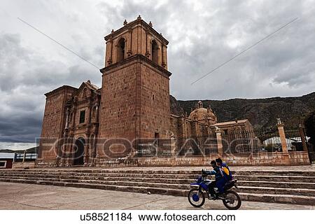 Picture - Two boys on motorcycle passing near old church. Fotosearch