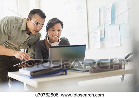 Two people working together with laptop View Large Photo Image Stock Photograph - Two people working together with laptop. Fotosearch