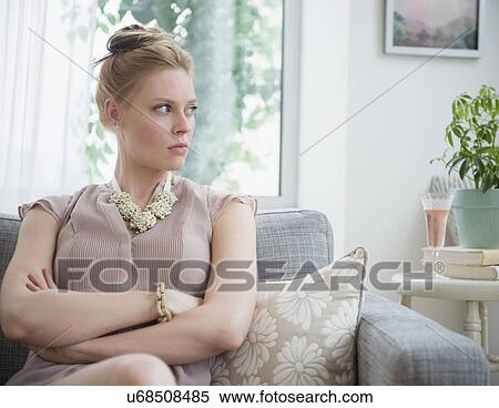 Stock Photography - Upset young woman sitting on sofa. Fotosearch