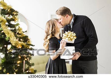 Stock Photography - Woman and man kissing at Christmas. Fotosearch
