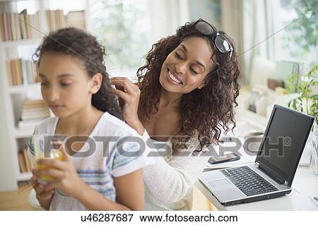Stock Photo - Woman braiding (8-9) daughter's hair. Fotosearch