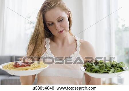 Stock Photo - Woman choosing between pasta and salad. Fotosearch