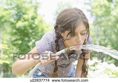 Woman drinking water from garden hose View Large Photo Image Picture - Woman drinking water from garden hose. Fotosearch