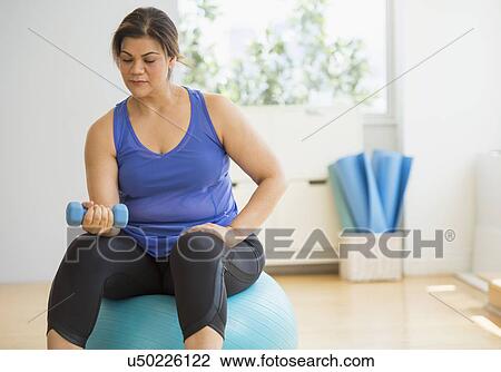 Stock Image - Woman exercising at gym. Fotosearch
