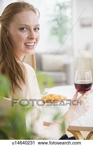 Stock Image - Woman having meal with red wine. Fotosearch