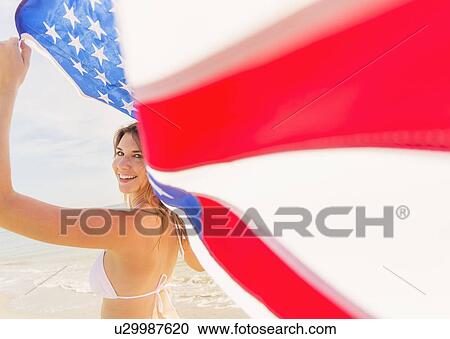 Stock Image - Woman holding American flag. Fotosearch