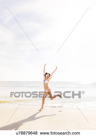Stock Photo - Woman jumping on beach. Fotosearch