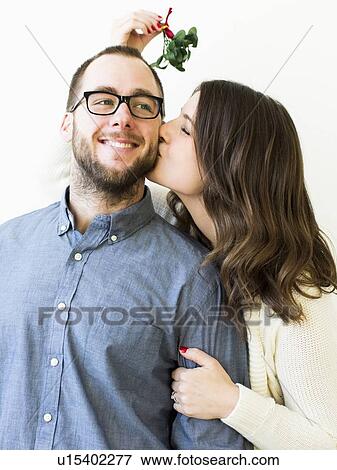 Woman kissing man under mistletoe View Large Photo Image Stock Photo - Woman kissing man under mistletoe. Fotosearch