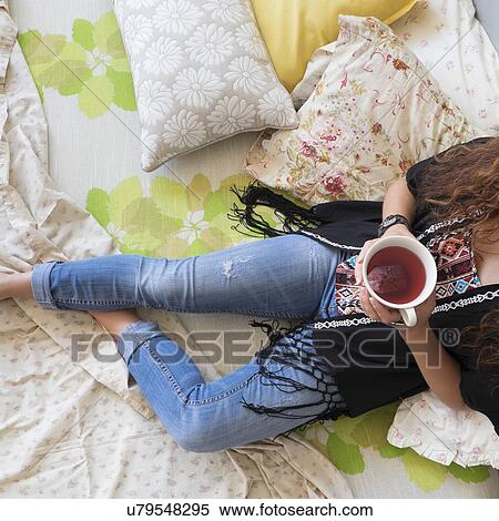 Woman lying down on bed with tea cup View Large Photo Image Stock Photography - Woman lying down on bed with tea cup. Fotosearch