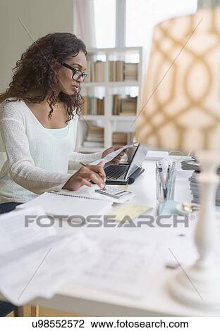 Stock Image - Woman paying bills via internet. Fotosearch