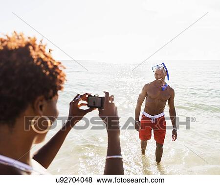 Woman photographing man on beach View Large Photo Image Stock Photo - Woman photographing man on beach. Fotosearch