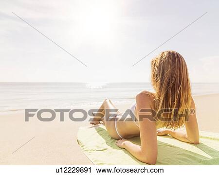Stock Image - Woman relaxing on beach. Fotosearch