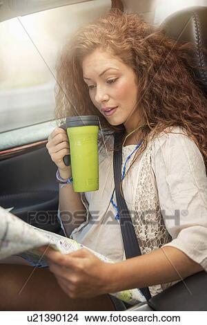 Woman sitting in car with map and disposable cup View Large Photo Image Picture - Woman sitting in car with map and disposable cup. Fotosearch