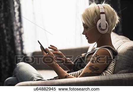 Woman sitting on sofa using digital tablet View Large Photo Image Stock Photography - Woman sitting on sofa using digital tablet. Fotosearch
