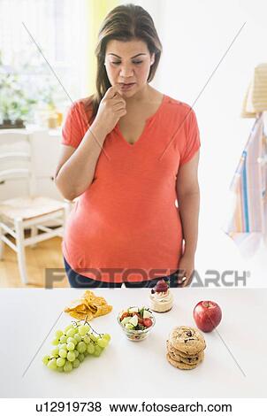 Stock Photo - Woman standing by counter in kitchen. Fotosearch