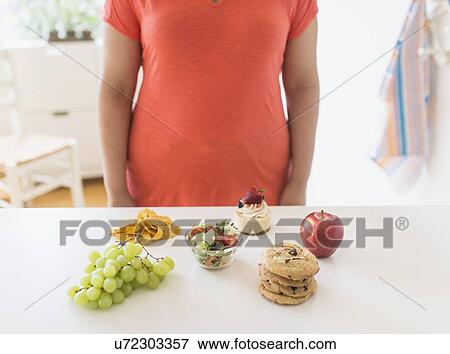 Stock Photo - Woman standing by counter in kitchen. Fotosearch