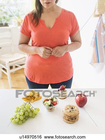 Stock Photograph - Woman standing by counter in kitchen. Fotosearch