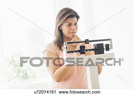 Stock Image - Woman standing on scale. Fotosearch