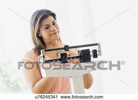 Stock Image - Woman standing on scale. Fotosearch