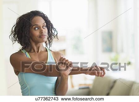 Stock Image - Woman stretching in living room. Fotosearch