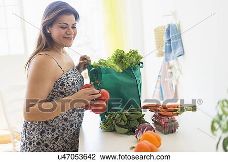 Woman taking out vegetables of grocery bag View Large Photo Image Stock Image - Woman taking out vegetables of grocery bag. Fotosearch