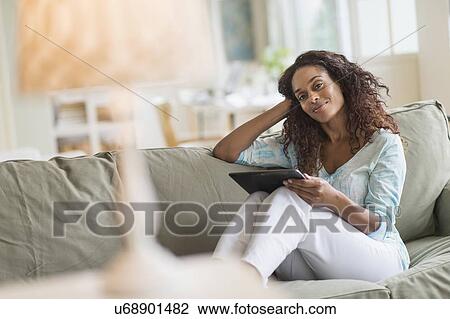 Woman using digital tablet on sofa View Large Photo Image Stock Image - Woman using digital tablet on sofa. Fotosearch