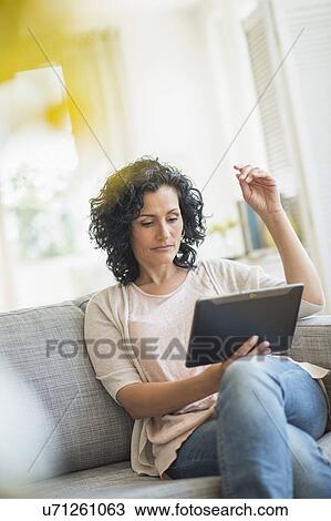 Stock Image - Woman using digital tablet on sofa. Fotosearch