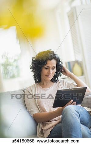 Woman using digital tablet on sofa View Large Photo Image Stock Photo - Woman using digital tablet on sofa. Fotosearch