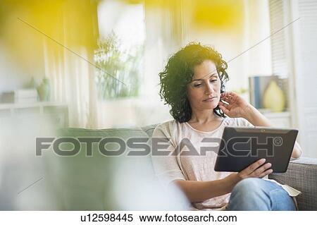 Woman using digital tablet on sofa View Large Photo Image Stock Photography - Woman using digital tablet on sofa. Fotosearch