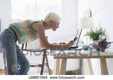 Woman using laptop and cell phone at home View Large Photo Image Picture - Woman using laptop and cell phone at home. Fotosearch