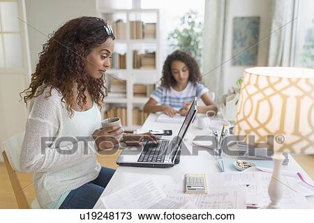 Woman using laptop at home, girl (8-9) doing homework in background View Large Photo Image Stock Image - Woman using laptop at home, girl (8-9) doing homework in background. Fotosearch