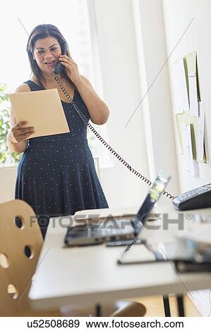 Woman using telephone in office View Large Photo Image Stock Photo - Woman using telephone in office. Fotosearch