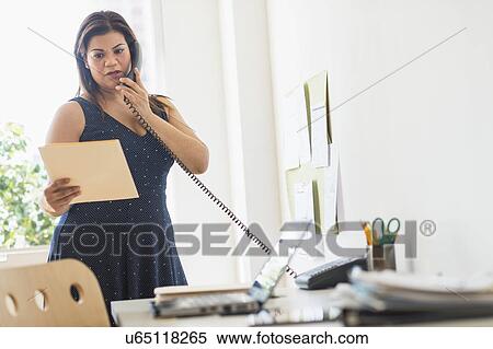 Stock Photography - Woman using telephone in office. Fotosearch