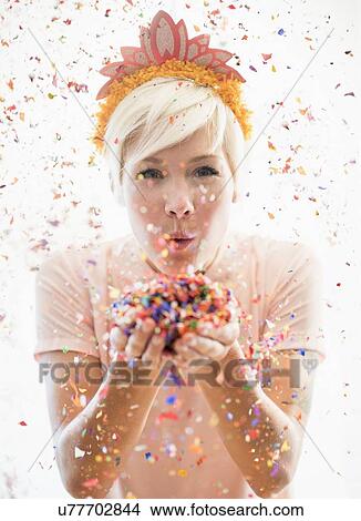 Woman wearing tiara blowing confetti View Large Photo Image Picture - Woman wearing tiara blowing confetti. Fotosearch