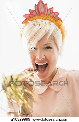 Woman wearing tiara blowing party horn blower View Large Photo Image Stock Photo - Woman wearing tiara blowing party horn blower. Fotosearch