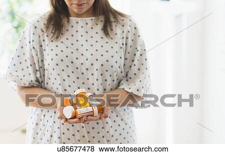 Stock Photo - Woman with pill bottles in hands. Fotosearch