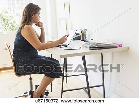 Stock Image - Woman working in home office. Fotosearch