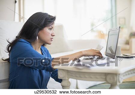 Stock Image - Woman working in living room. Fotosearch