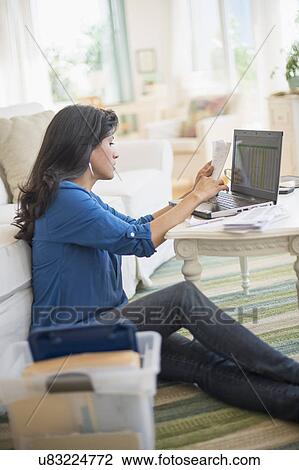 Stock Image - Woman working in living room. Fotosearch