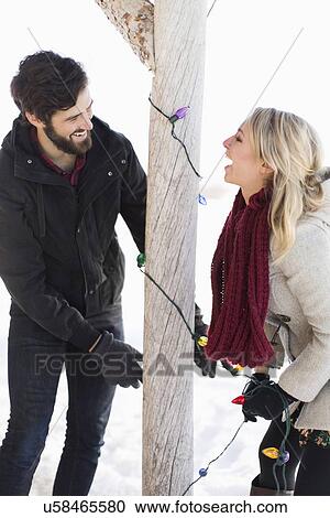 Stock Image - Young couple decorating house with christmas lights. Fotosearch