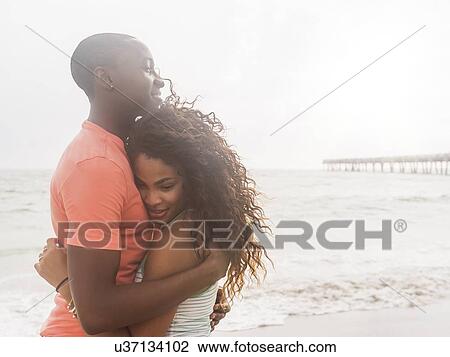 Young couple embracing on beach View Large Photo Image Stock Image - Young couple embracing on beach. Fotosearch