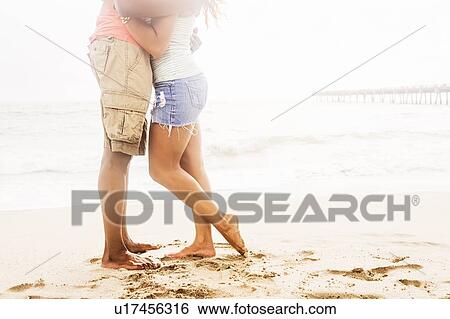 Stock Photograph - Young couple embracing on beach. Fotosearch