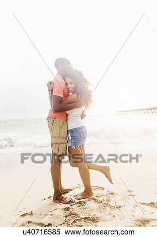 Stock Photography - Young couple embracing on beach. Fotosearch