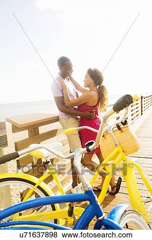 Stock Photo - Young couple embracing on boardwalk. Fotosearch
