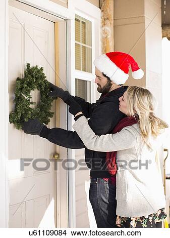 Young couple hanging wreath on door View Large Photo Image Picture - Young couple hanging wreath on door. Fotosearch