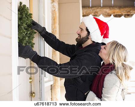 Young couple hanging wreath on door View Large Photo Image Stock Image - Young couple hanging wreath on door. Fotosearch