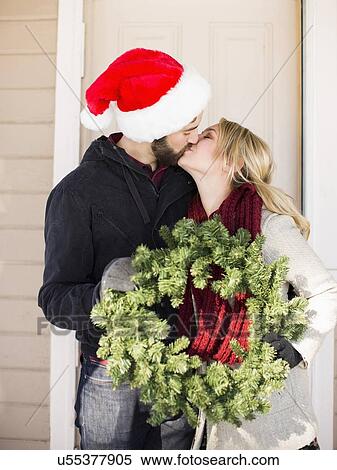 Stock Photography - Young couple holding wreath and kissing. Fotosearch