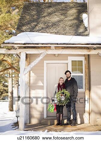 Young couple holding wreath standing in front of house View Large Photo Image Stock Image - Young couple holding wreath standing in front of house. Fotosearch
