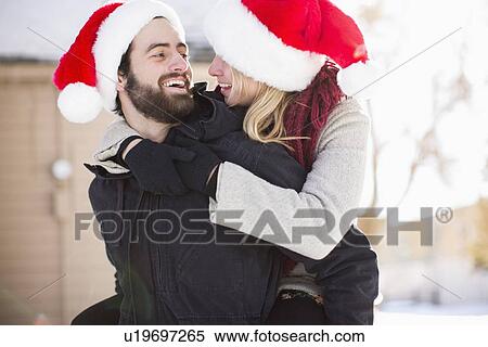 Young couple in santa hats, piggyback View Large Photo Image Stock Photography - Young couple in santa hats, piggyback. Fotosearch